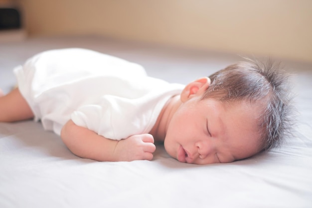 Asiatisches Baby schläft auf grauem Bett