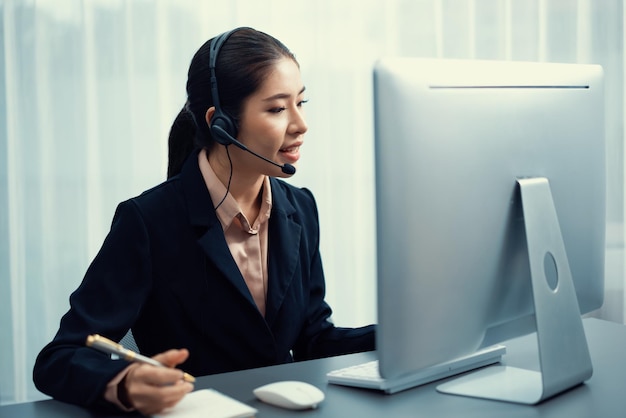 Asiatisches Callcenter mit Headset und Mikrofon, das auf ihrem Laptop arbeitet Weibliche Betreiberin bietet außergewöhnlichen Kundenservice Unterstützendes Callcenter-Agent, das Kunden bei Anfragen hilft Enthusiastisch