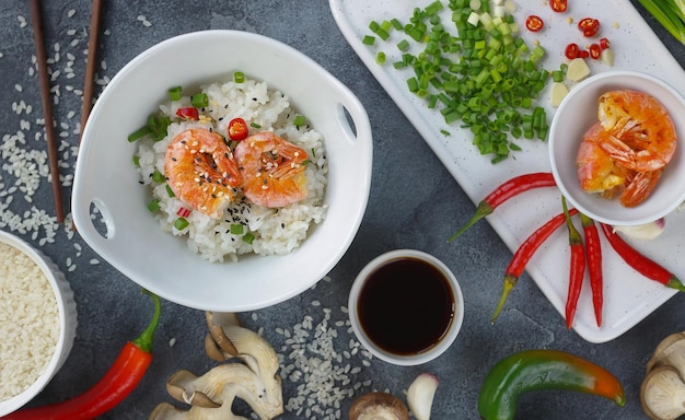 Asiatisches Essen auf dunklem Hintergrund, Wok-Reis mit Garnelen und Pilzen, während der Zubereitung, horizontal, Ansicht von oben