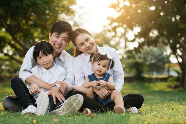 Asiatisches Familienporträt mit den glücklichen Menschen, die am Park, am Lebensstil und am Feiertags-Konzept lächeln