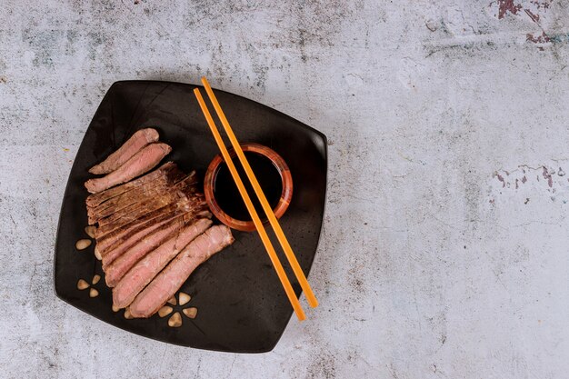 Asiatisches gegrilltes Steak mit Sojasoße und Essstäbchen.