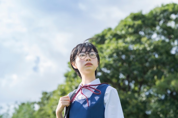 Asiatisches Highschool-Mädchen mit den Gläsern, die den Himmel betrachten