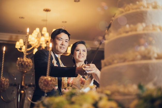 asiatisches Hochzeitspaar vor Kuchen