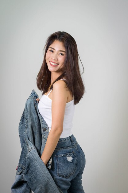 asiatisches hübsches Frauenportrait mit schönem Haar lokalisiertem Hintergrund mit Baumwollstoff- und Denimjacke