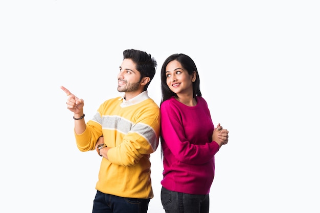 Asiatisches indisches Paar trägt bunte warme Pullover oder wollene Winterkleidung und steht isoliert vor weißem Hintergrund