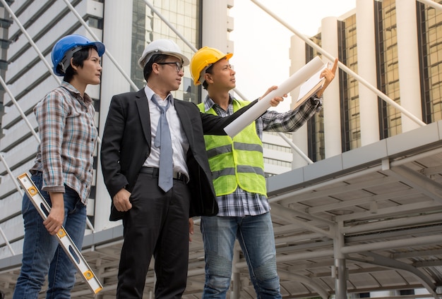 Asiatisches Ingenieur- und Architektenteam, das Bau an der Baustelle überprüft