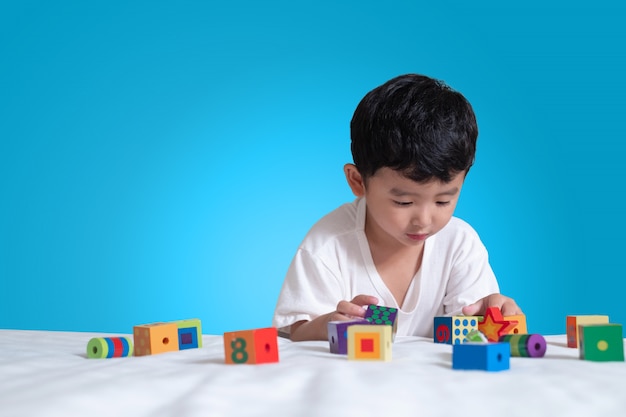 Asiatisches Jungenspielquadratblock-Puzzlespielspielzeug auf dem Bett