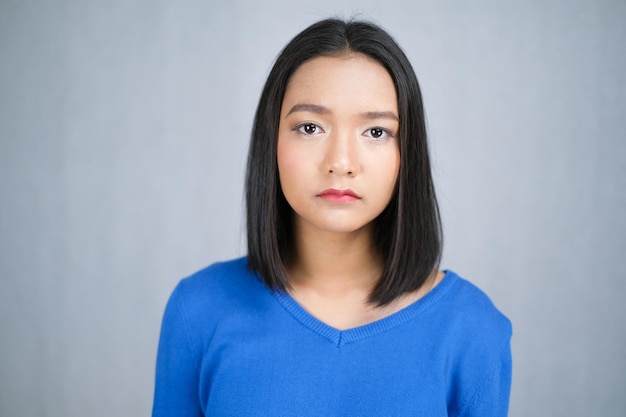 Asiatisches junges Mädchen trägt blauen Pullover auf weißem Hintergrund