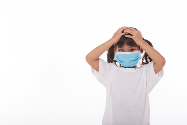 Asiatisches Kind, das eine medizinische Maske trägt, fühlt Kopfschmerzen auf Weiß