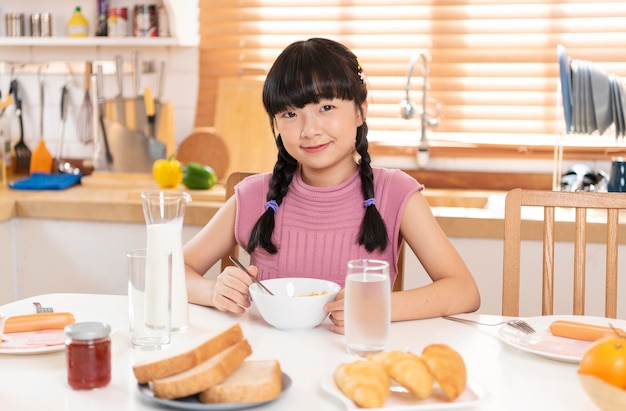 Asiatisches Kind isst gerne Müsli und Milchfrühstück im Küchenraum bei homexA