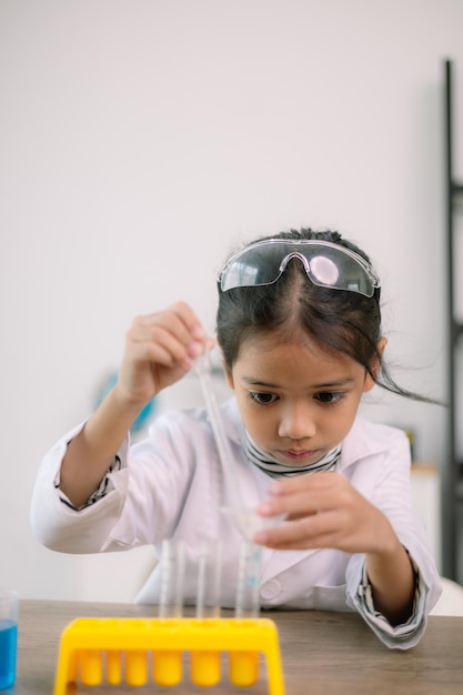 Foto asiatisches kind lernt chemie mit reagenzrohr, macht experimente im labor, unterrichtet chemie und kinderkonzepte, frühe entwicklung von kindern