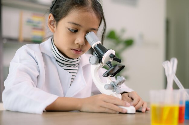 Foto asiatisches kind lernt chemie mit reagenzrohr, macht experimente im labor, unterrichtet chemie und kinderkonzepte, frühe entwicklung von kindern