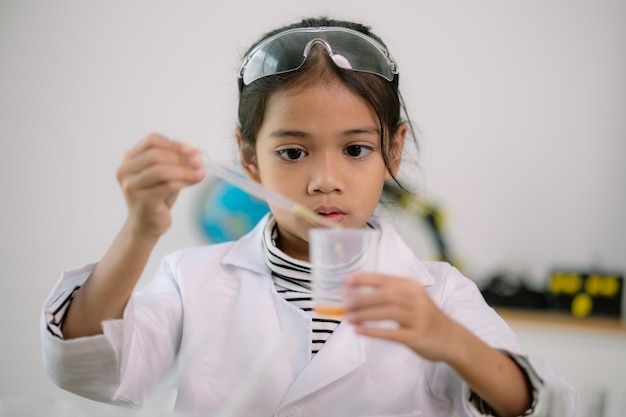 Foto asiatisches kind lernt chemie mit reagenzrohr, macht experimente im labor, unterrichtet chemie und kinderkonzepte, frühe entwicklung von kindern