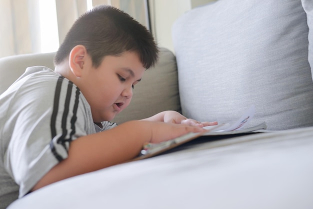 Asiatisches Kind liest zu Hause ein Buch. Bildungskonzept