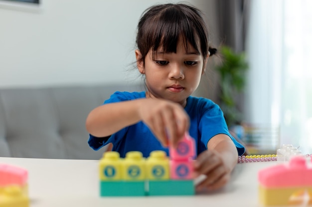 Asiatisches Kindermädchen, das kreative Spielzeugblöcke für Homeschooling spielt