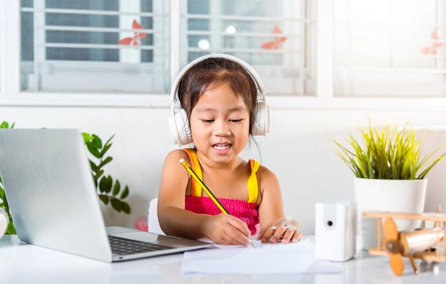 Asiatisches Kindermädchen, das zu Hause Videokonferenz-Fernbildung studiert