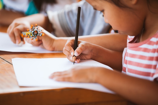 Asiatisches Kindermädchen, das zusammen mit ihrem Freund mit Spaß zeichnet und malt