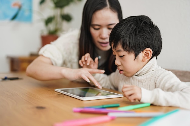 Asiatisches Kindermädchen und Vorschulkinder lernen mit digitalem Tablet im Innenbereich - Kindertagesstätte und Technologiekonzept