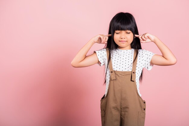 Asiatisches kleines Kind 10 Jahre alt Schließen Sie ihre Ohren mit Fingern und Augen