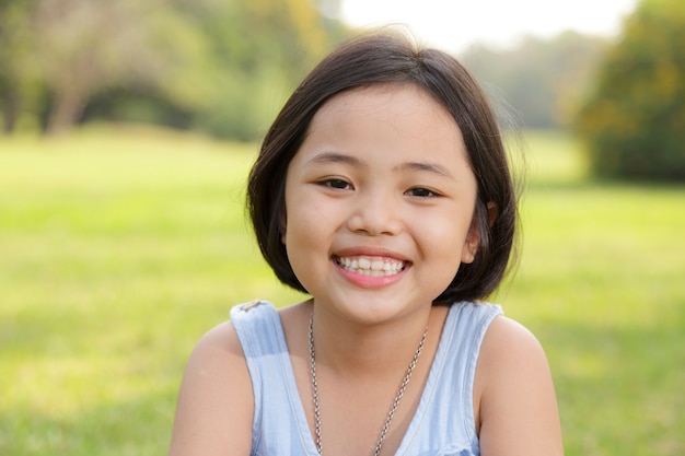 Asiatisches kleines Mädchen, das glücklich im Park lächelt
