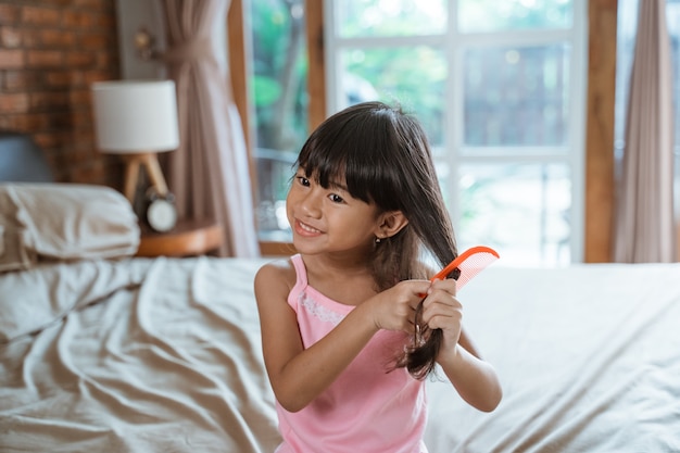 Asiatisches kleines Mädchen, das Haare kämmt