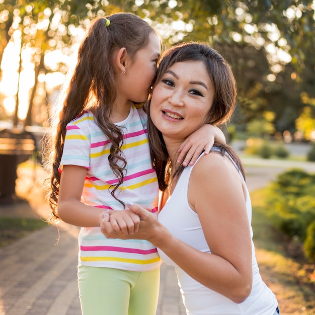 Asiatisches kleines Mädchen, das ihre Mutter küsst