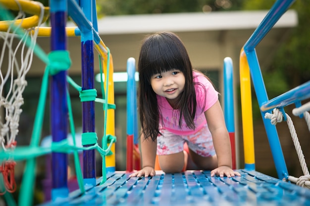Asiatisches kleines Mädchen genießt, in einem Kinderspielplatz zu spielen