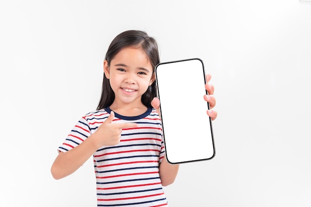 Asiatisches kleines Mädchen hält Smartphone-Attrappe mit leerem Bildschirm in der Hand und lächelt auf weißem Hintergrund