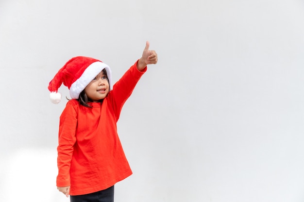 Asiatisches kleines Mädchen in roter Weihnachtsmütze auf weißem Hintergrund.