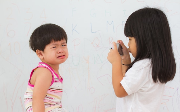 Asiatisches kleines Mädchen machen ein Foto, weinen kleiner Junge.