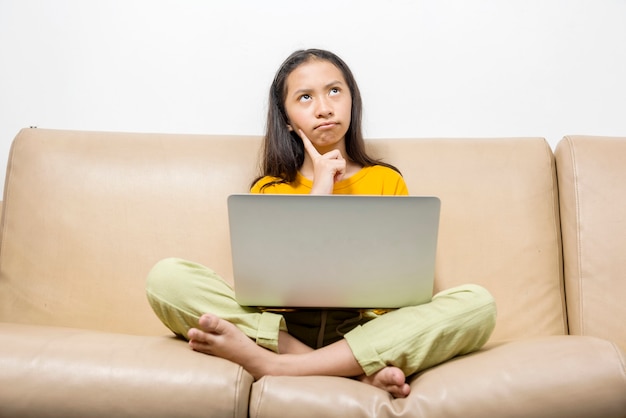 Asiatisches kleines Mädchen mit Laptop, das zu Hause an der Online-Schulklasse teilnimmt. Online-Bildung während der Quarantäne