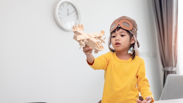 Asiatisches kleines Mädchen spielt zu Hause mit einem Spielzeugflugzeug, das sie Pilot werden will Dreamer-Pilot