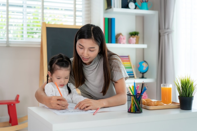 Asiatisches kleines Mädchen und ihre Mutter, die Hausaufgaben machen