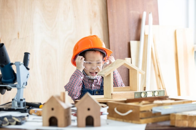 Asiatisches kleines Mädchen Zimmermann arbeitet an Holzbearbeitung in der Tischlerei Zimmermann arbeitet an Holzhandwerk in der Werkstatt Baumaterial Holzmöbel Asiatisches kleines Mädchen arbeitet in einer Tischlerei