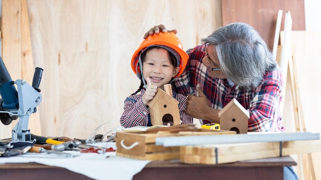 Asiatisches kleines Mädchen Zimmermann arbeitet an Holzbearbeitung in der Tischlerei Zimmermann arbeitet an Holzhandwerk in der Werkstatt Baumaterial Holzmöbel Asiatisches kleines Mädchen arbeitet in einer Tischlerei