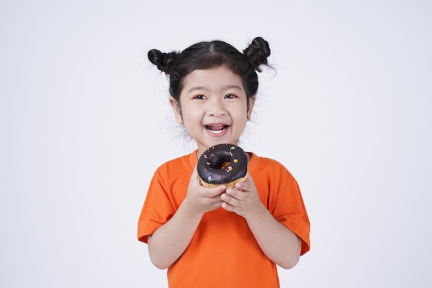 Asiatisches kleines süßes Mädchen, das großen Donut isst