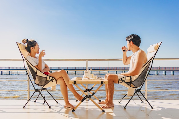 Asiatisches Liebespaar genießt ihren Urlaub am Meer im Sommer mit wunderschönem klarem Himmel und Meerblick