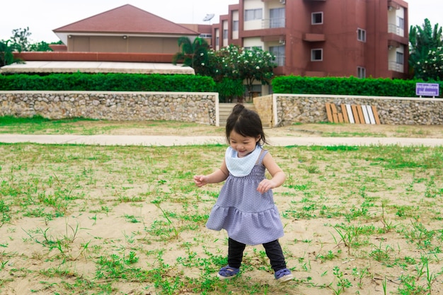 Asiatisches Mädchen, das auf dem Spielplatz spielt und Spaß im Park hat