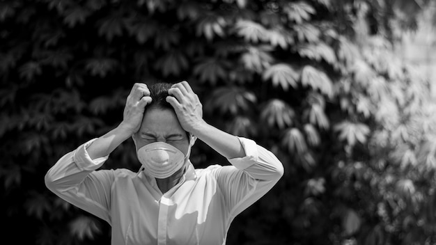 Asiatisches Mädchen, das die Belastung fühlt und eine Maske trägt. - Schutz vor Viren, Infektionen, Abgasen und Industrieemissionen.