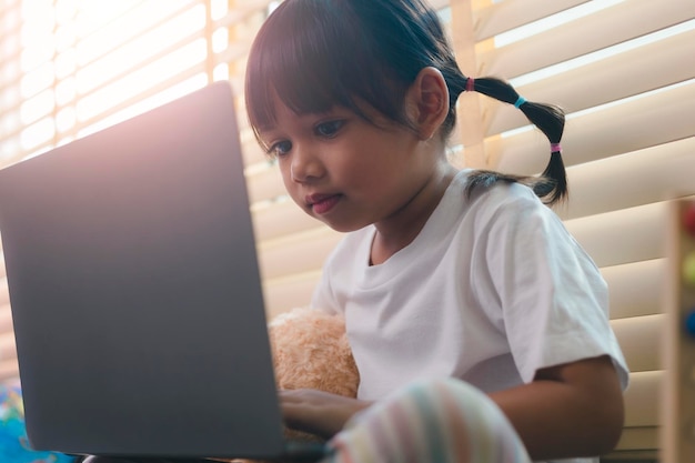 Asiatisches Mädchen, das einen Laptop-Computer für das Online-Lernen zu Hause während der häuslichen Quarantäne verwendet