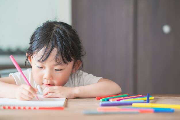 Asiatisches Mädchen, das mit bunten Stiften zeichnet