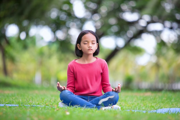 asiatisches Mädchen, das Yogahaltung im Park im Freien tut