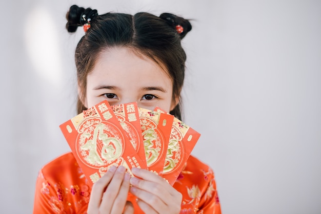 Foto asiatisches mädchen des glücklichen chinesischen neujahrsfests, das rote umschläge hält