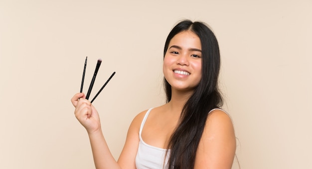 Asiatisches Mädchen des jungen Jugendlichen, das Make-upbürste hält