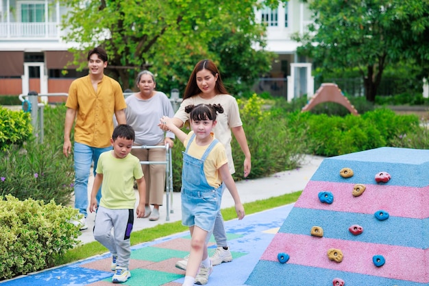 Asiatisches Mädchen fällt beim Laufen zusammen mit Mutter und jungem Bruder Familie kümmert sich um den Spielplatz