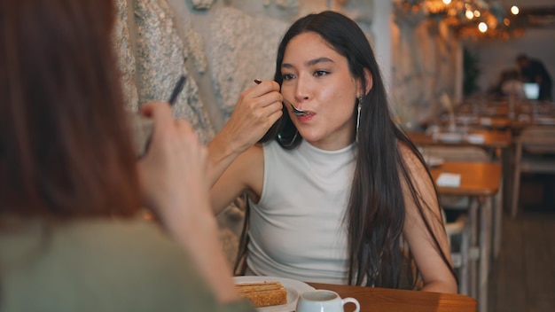 Asiatisches Mädchen genießt ein köstliches Dessert mit einem Freund in der Cafeteria