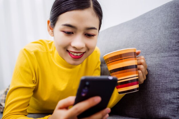 Asiatisches Mädchen liegend ruhen zu Hause auf Sofa im Wohnzimmer, das glücklich fühlt.