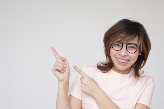 Asiatisches Mädchen mit Brille zeigt Zeigefinger nach oben