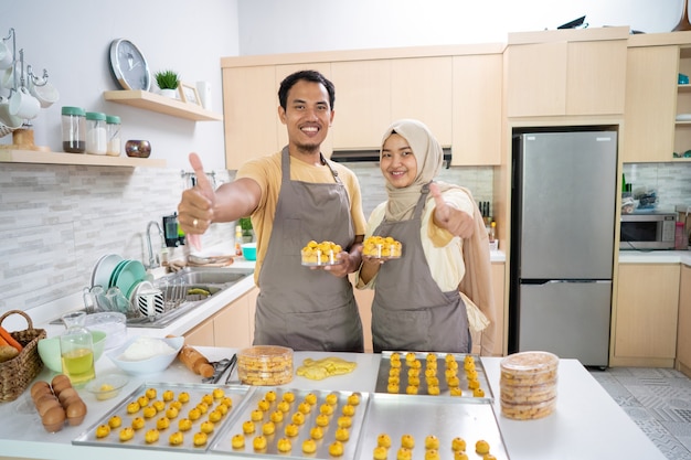 Asiatisches muslimisches Paar, das Nastar-Imbisskuchen zusammen in der Küche macht