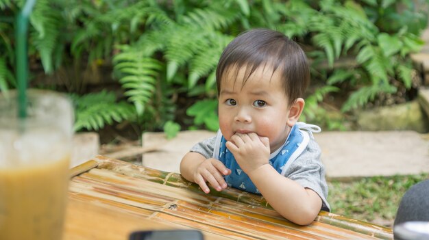 Asiatisches nettes Kind, das einen Snack in einem Garten isst.
